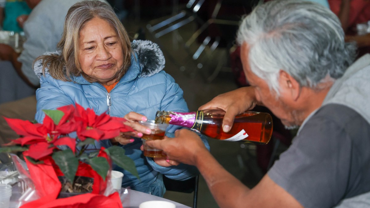 Un hombre sirviendo sidra en una copa a su acompañante.