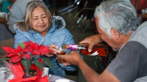 Un hombre sirviendo sidra en una copa a su acompañante.