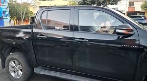 Conductor con playera blanca dormido al interior de una camioneta negra con la puerta abierta estacionada sobre la Avenida Ávila Camacho en Guadalajara