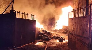 Vista del exterior de una planta recicladora ardiendo en llamas en su interior con las puertas abiertas de par en par durante la madrugada