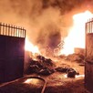 Vista del exterior de una planta recicladora ardiendo en llamas en su interior con las puertas abiertas de par en par durante la madrugada