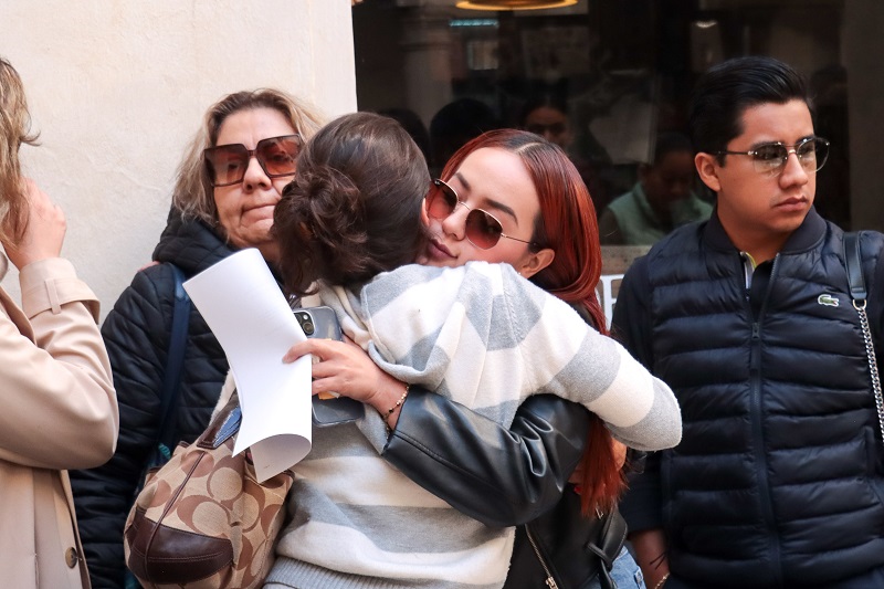 Dos mujeres abrazadas frente a una multitud.