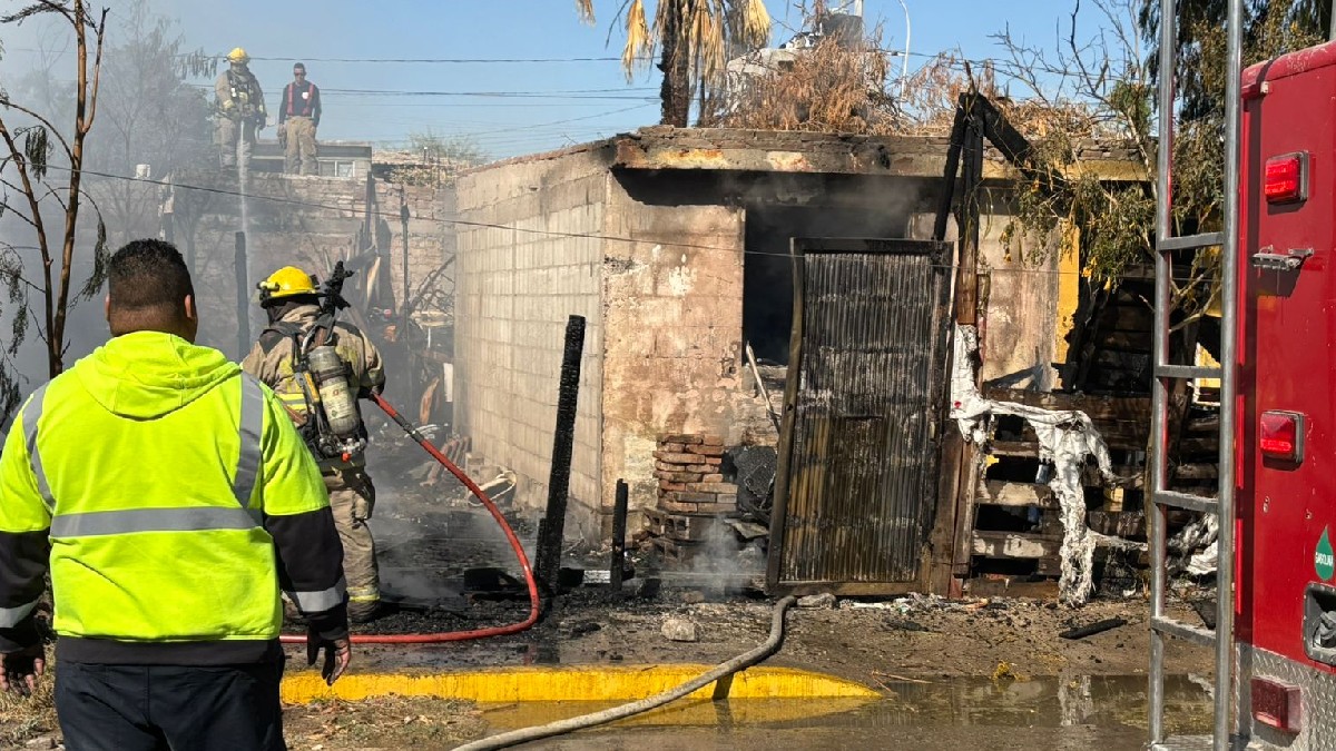 Casa incendiada y personal de Bomberos.