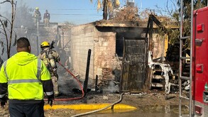 Casa incendiada y personal de Bomberos.