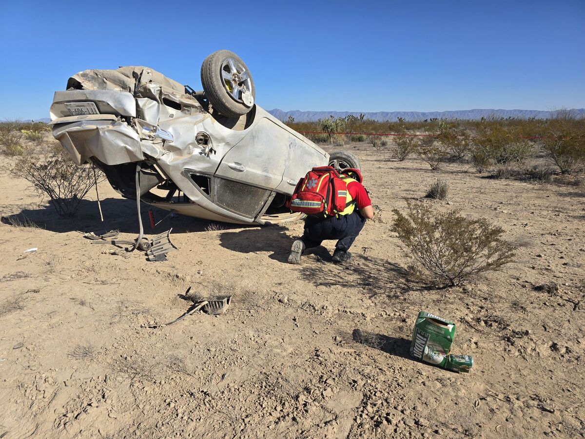 Automóvil volcado en carretera y con un cartón de cervezas a un lado.