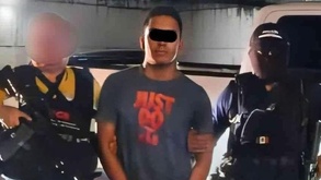 Un hombre detenido con una cinta negra sobre los ojos por su presunción de inocencia.