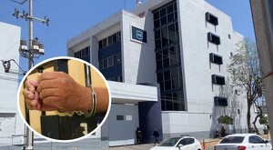 Vista exterior de las instalaciones de la Fiscalía del Estado de Jalisco con un globo de imagen de una persona con esposas en las muñecas