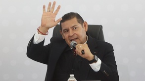 Un señor vestido de traje con un micrófono en la mano y levantando otra de sus manos.