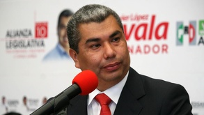 Un hombre hablando frente a un micrófono en un evento del PRI en México.