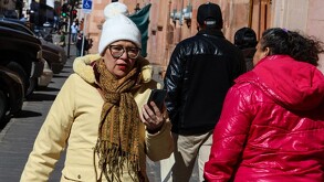 Se observa a una señora con chamarra beige y gorro blanco.
