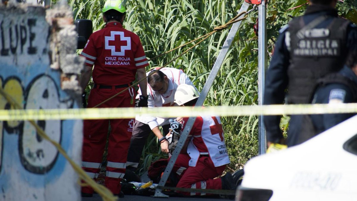 Grupo de paramédicos reunidos alrededor de una persona sin vida en un camino de terracería.