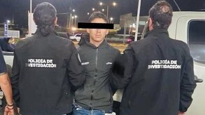 Ángel Yael 'N' viendo de frente con los ojos censurados con dos policías de la Fiscalía de Jalisco agarrándolo de los brazos