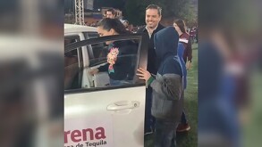 Alcalde de Tequila, Diego Rivera, entregando un auto blanco con logos de Morena a una mujer y sus hijos durante posada navideña