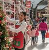 Trabajadora mujer durante una jornada en Navidad en un centro comercial. Imagen generada con Gemini AI