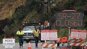 Se observa a equipos de trabajo en un cierre vial en la Ruta Estatal 27 y la Carretera de la Costa del Pacífico debido a las fuertes tormentas en California.