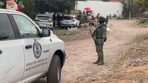 Imagen de un soldado en una terracería en donde ocurrió un homicidio, portando un arma.
