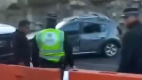 Policías resguardando un vehículo chocado en una carretera.