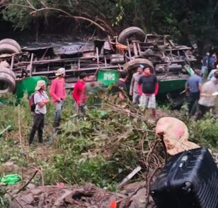 Personas alrededor de un autobús de pasajeros volcado en un río de Veracruz.