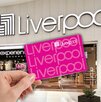 Aspecto de una tienda Liverpool en México, con una mano sobrepuesta cargando una tarjeta de la tienda.