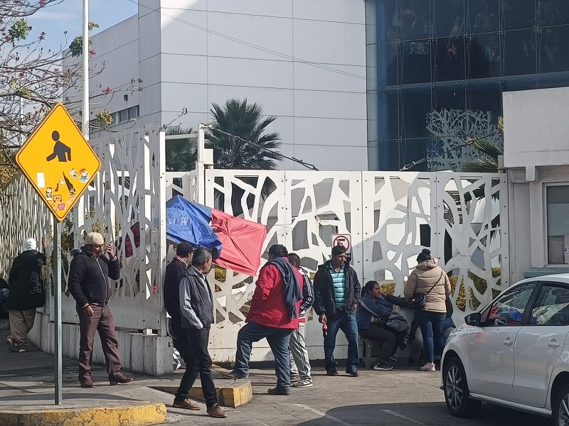 Personas afuera de una reja que protege a un hospital.