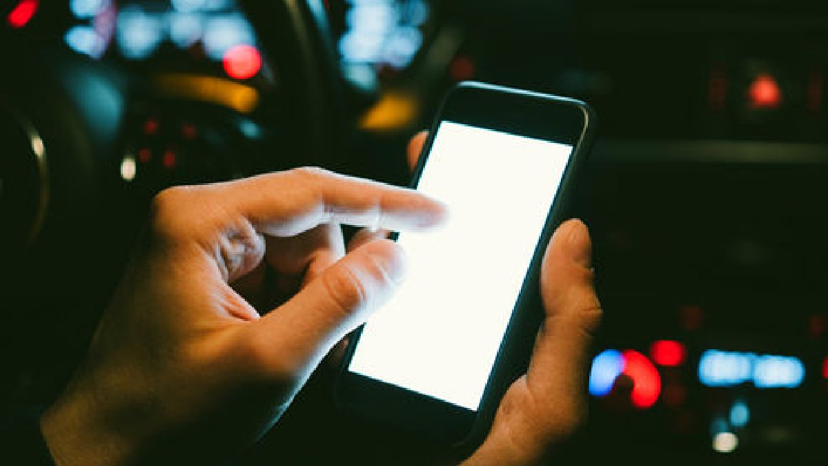 Mano sosteniendo un celular dentro de un automóvil