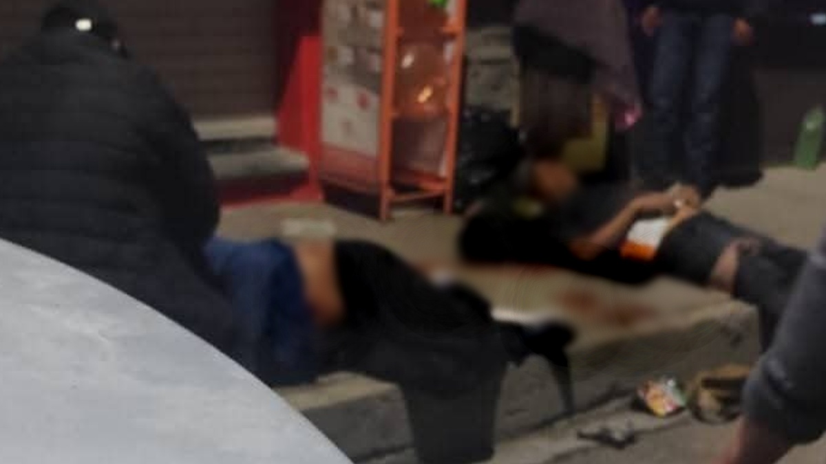 Dos hombres heridos de bala tirados en el suelo.