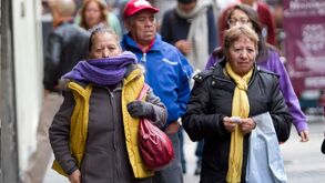 Personas con frío caminando en la Comarca Lagunera, usando chamarras y bufandas.