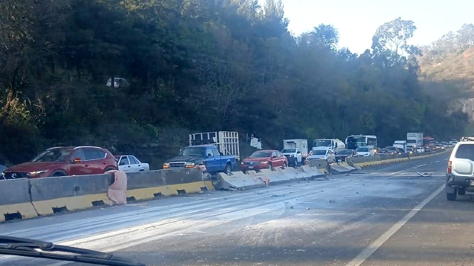 Larga fila de automóviles en la carretera Morelia-Pátzcuaro entre un muro de un contención y un cerro