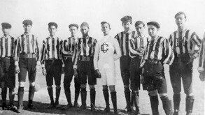 Fotografía antigua en blanco y negro de los integrantes del primer equipo del Club Guadalajara (Chivas), posando con uniformes de rayas verticales.