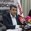 Un hombre habla frente a micrófonos de prensa en una mesa; detrás hay una lona sobre el Poder Judicial y una bandera blanca con el logo de Morena.