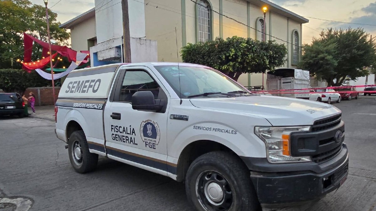 Peritos y policías trabajan junto a una camioneta blanca de la Fiscalía General (SEMEFO) en una zona acordonada bajo la sombra de un árbol.