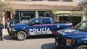 Una patrulla tipo pick-up azul de la Policía de Tonalá estacionada frente a una casa y un comercio local llamado 