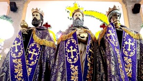 Tres figuras religiosas monumentales de los Reyes Magos, vestidas con capas de terciopelo morado y dorado, dentro de un templo decorado.