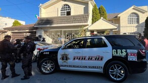 Se observa una camioneta que dice GRS y muchas personas afuera de casa color beige.