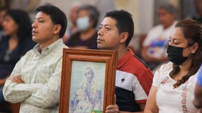 Un grupo de personas cargan una imagen religiosa al interior de una iglesia.