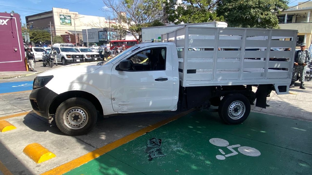 Un gran árbol de Navidad iluminado domina una plaza nocturna llena de gente y puestos de madera decorados con luces doradas en un mercado festivo.