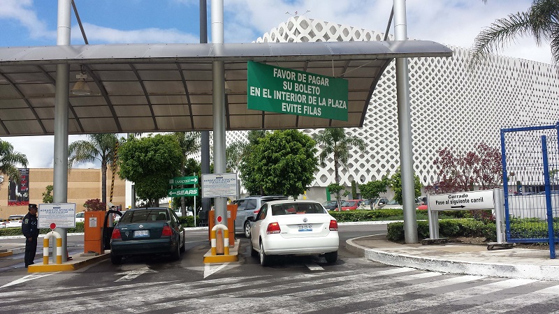 Vehículos ingresando a un área de estacionamiento en un centro comercial.