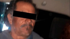 Fotografía de un hombre de avanzada edad detenido, con los ojos cubiertos.