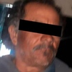 Fotografía de un hombre de avanzada edad detenido, con los ojos cubiertos.