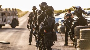 Se ve a un grupo de poliçías con el rostro cubierto y portando uniforme negro.