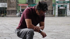 Un hombre hincado afuera de la Catedral de Puebla.