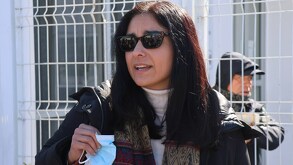 Una mujer con gafas oscuras hablando frente a una cámara.