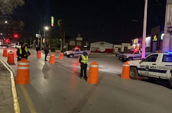 Se observa a unos policías de tránsito en la vialidad y a unos carros en tránsito.