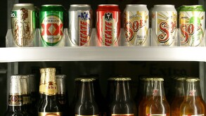 Se observan varias latas de cerveza dentro de un refrigerador.