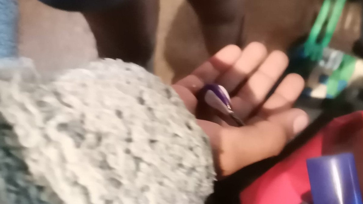 Una ambulancia de Protección Civil y Bomberos con las puertas traseras abiertas y luces encendidas está estacionada de noche frente a un edificio.