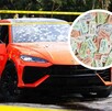 Un auto deportivo naranja con impactos de bala en el parabrisas está acordonado; un círculo superpuesto muestra boletos de rifa de colores.