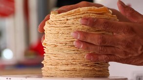 Una mano humana acomoda una serie de tortillas en una báscula.