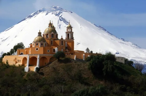 una iglesia y un volcán al fondo