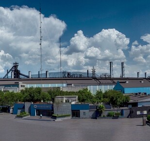 S eobserva un edificio grande color azul y unas nubes.