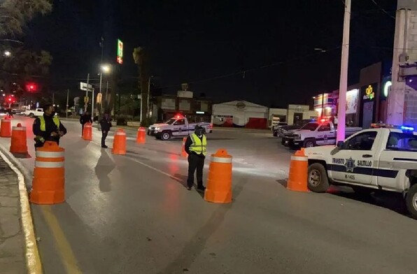 Se observa a unos policías de tránsito en la vialidad y a unos carros en tránsito.